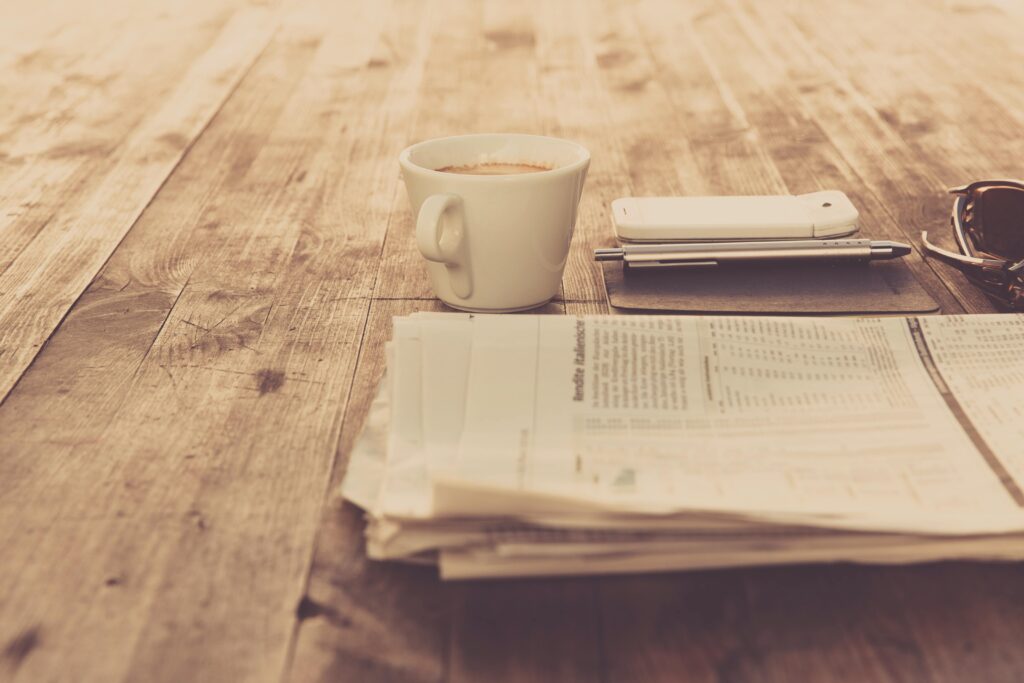 pexels-photo-97050-97050 A warm vintage morning setup with coffee, newspaper, and smartphone on wooden table.